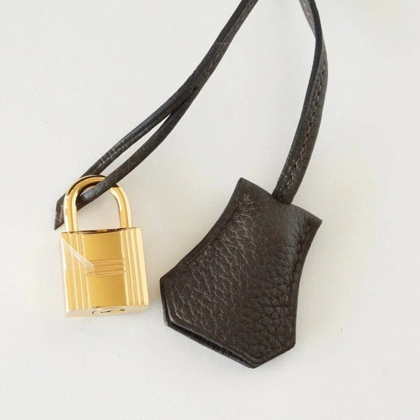 Deep Bronzed Olive Matte Pebbled Grain Spacious Structured Hand Tote With Cross Front Golden Lock Plates, Matching Suspended Textured Tag And Ridged Golden Metal Padlock Charm