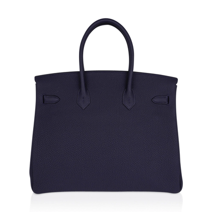 Saturated Midnight Navy Soft Subtle Pebbled Grain Roomy Structured Hand Tote With Seamless Uniform Stitching, Polished Golden Twist Lock Hardware And Matching Suspended Textured Tag Striped Metal Padlock Charm