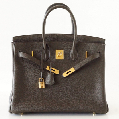Deep Bronzed Olive Matte Pebbled Grain Spacious Structured Hand Tote With Cross Front Golden Lock Plates, Matching Suspended Textured Tag And Ridged Golden Metal Padlock Charm